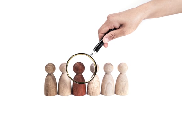 hand-holding-magnifying-glass-red-figurine-row