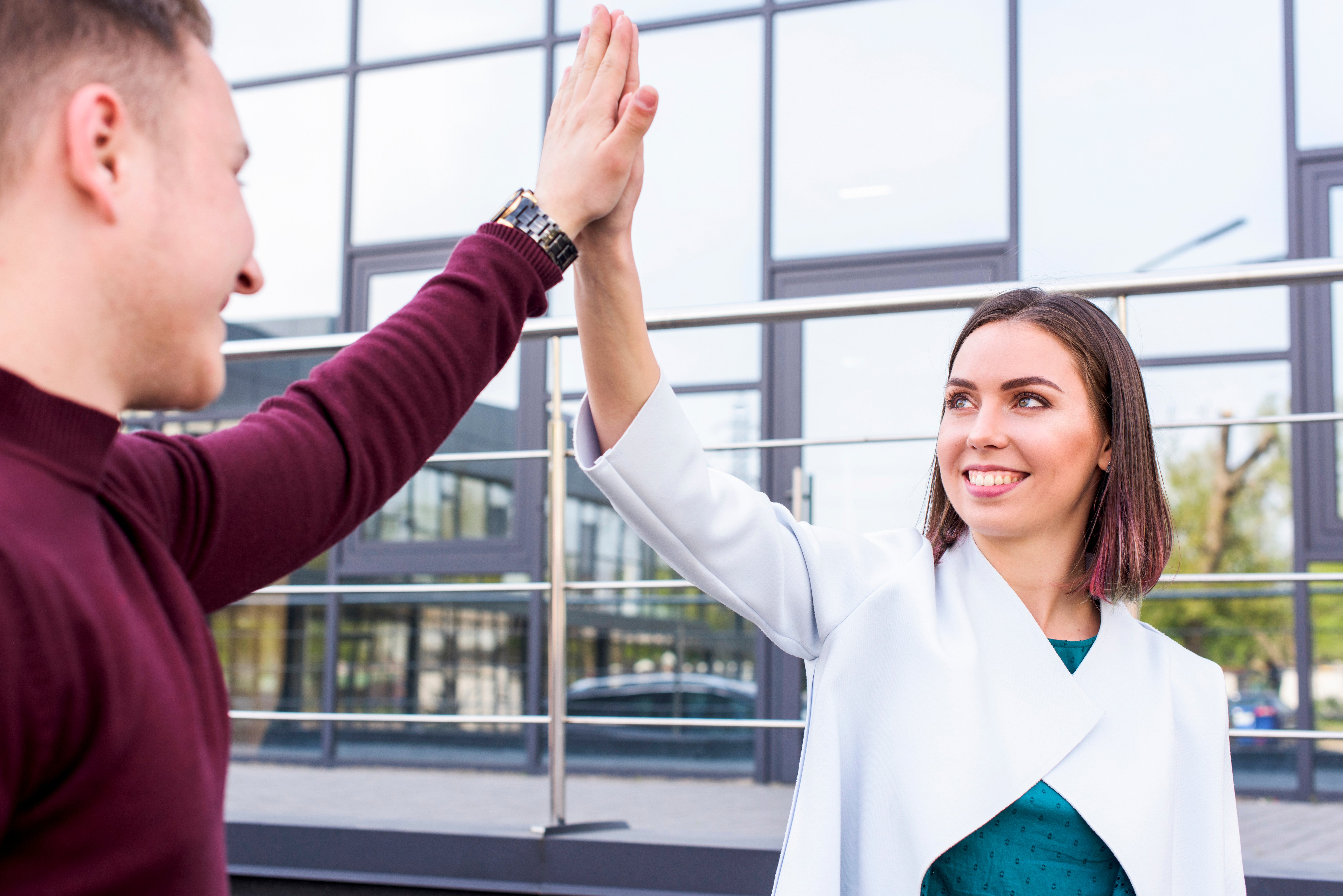 happy-young-male-female-friend-giving-high-five-outside